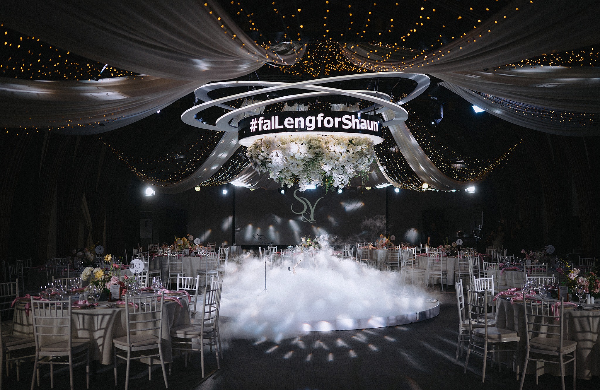 Elegant wedding venue with floral arrangements, draped ceilings, and ambient lighting.